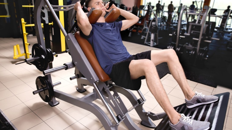 person in gym on hack squat machine