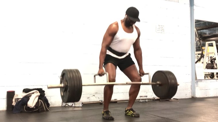 muscular person in gym doing trap bar deadlift