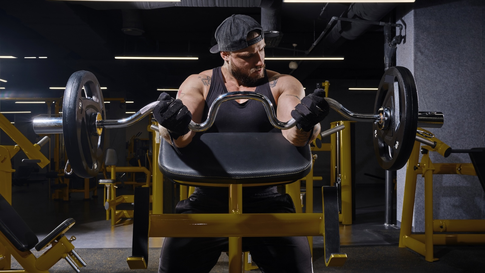 Man wearing workout gloves performs a preacher curl.